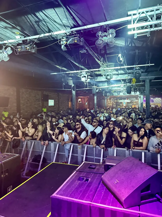 View from the stage over a packed club crowd under purple and white lights.