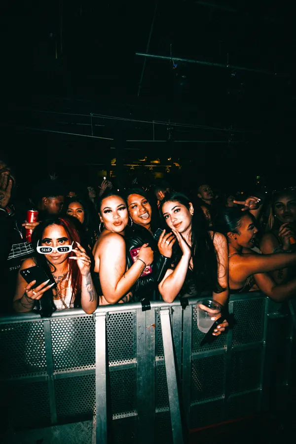 Front-row fans smiling at the barrier during a club show.