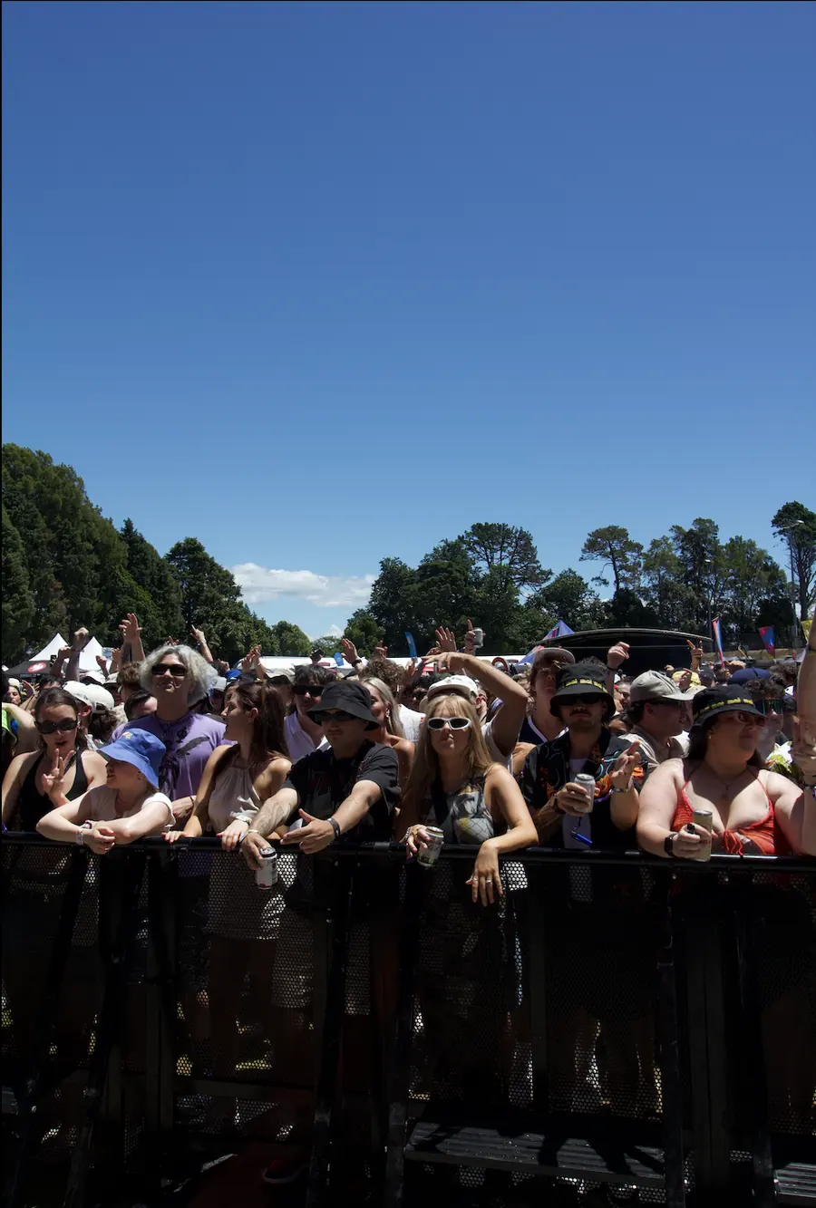 Packed outdoor festival crowd under a blue sky.