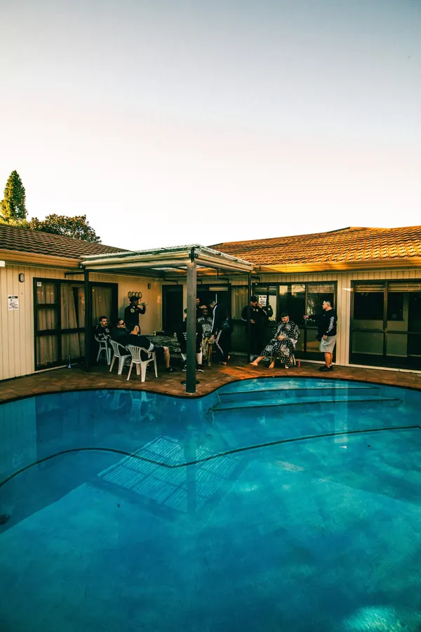 Backyard pool at dusk with guests gathered on the patio at a private party.