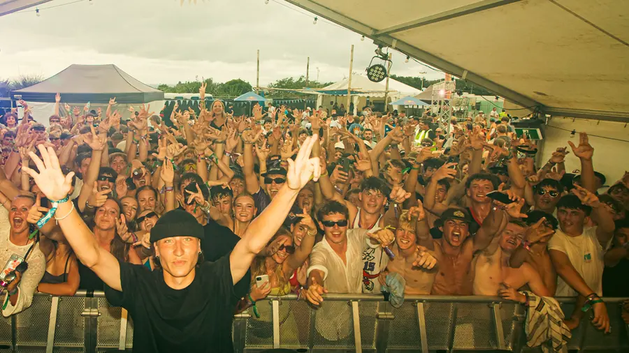 Festival crowd with hands up in front of the stage.